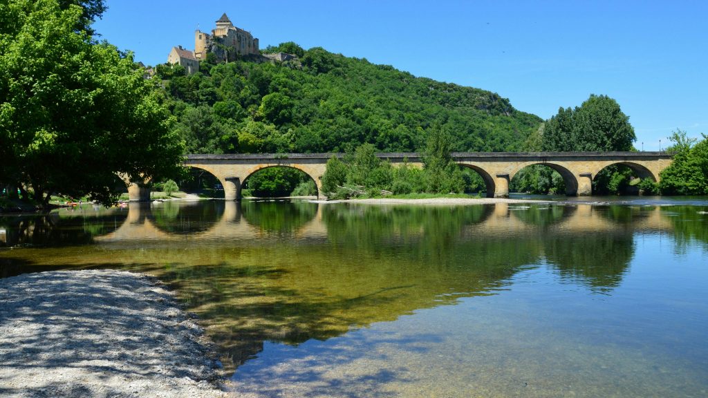 Stunning view of Castelnaud-La-Chapelle castle and bridge reflecting in the Dordogne River.