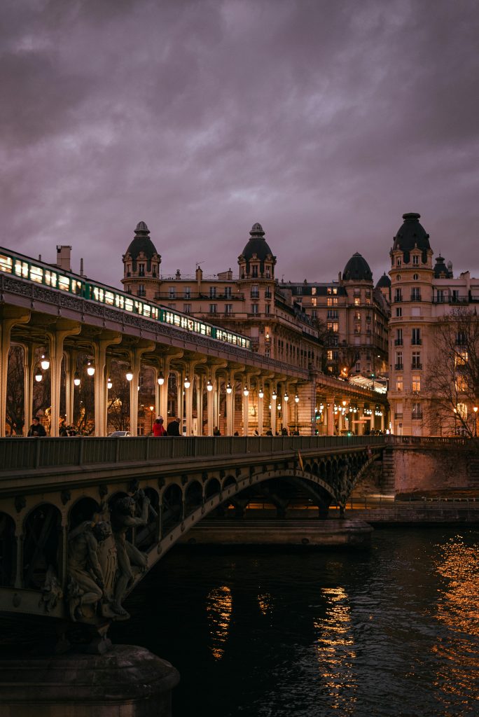 Stunning view of a Parisian bridge and classic architecture at dusk over the Seine River.