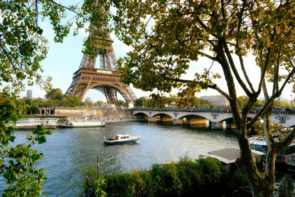 Captivating view of Eiffel Tower over Seine River with lush trees in Paris, France.