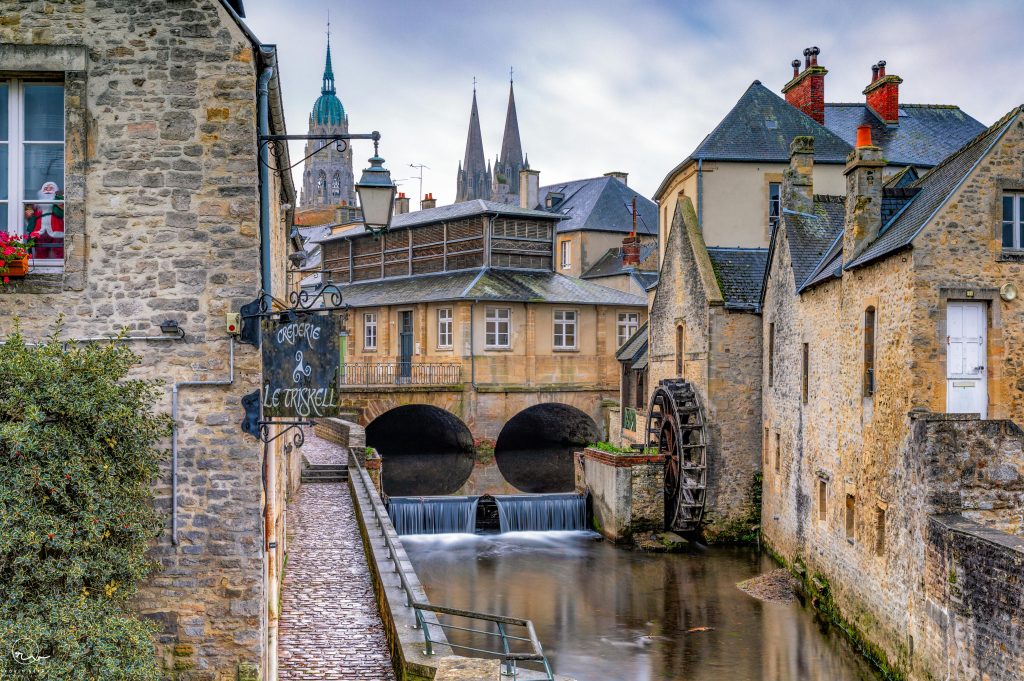 Historic watermill on a picturesque canal in Bayeux, France, showcasing Normandy's charm.