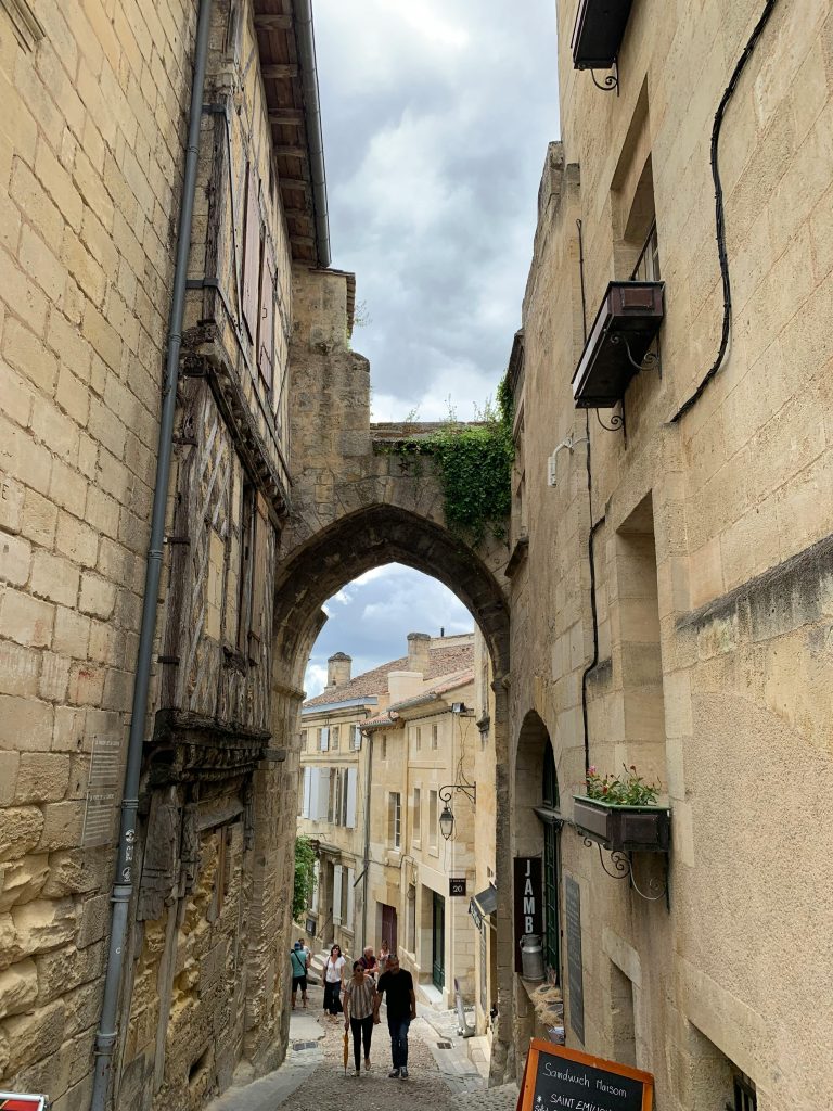 Charming medieval street in Saint-Émilion with historic stone buildings and archway.