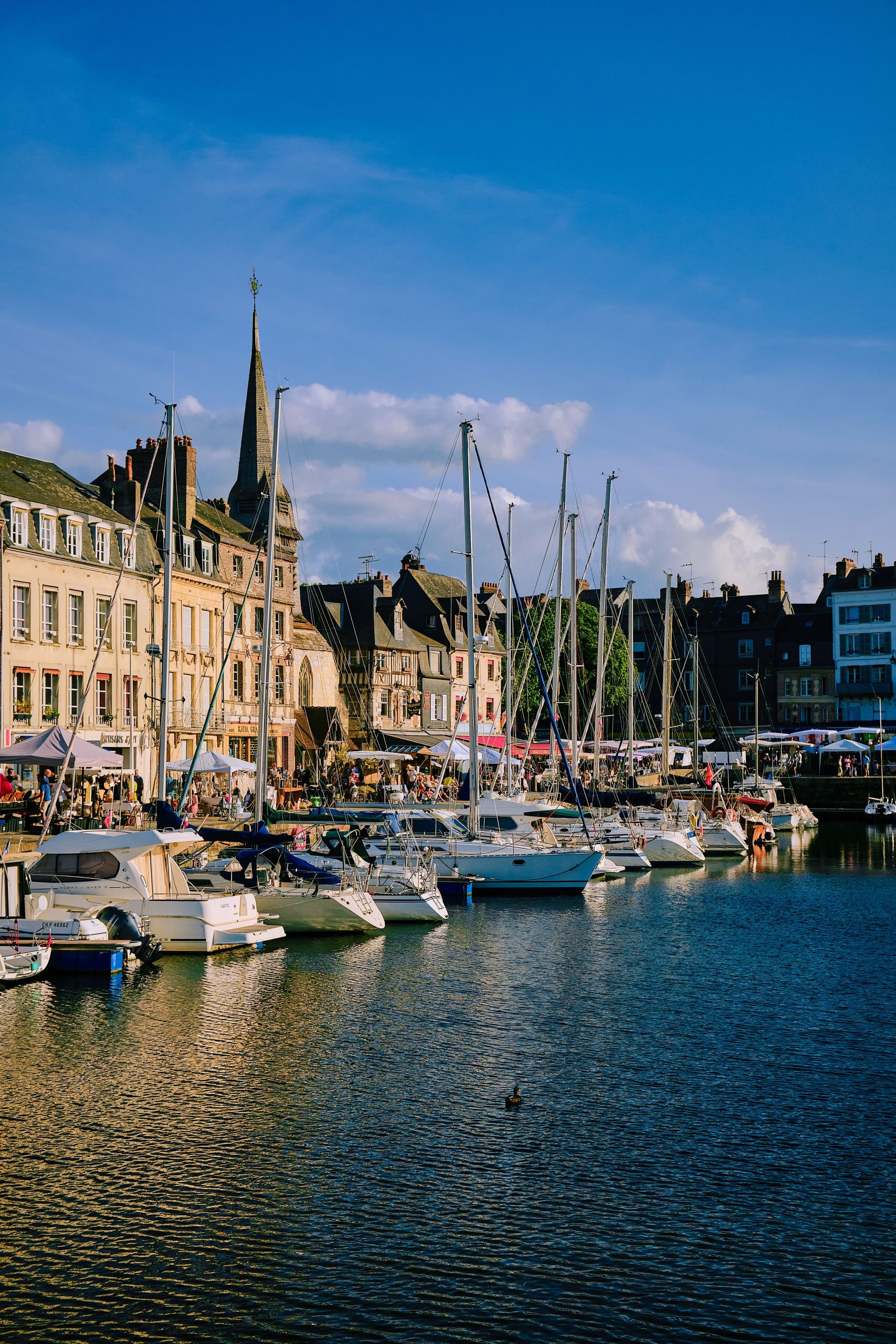 Scenic view of Honfleur Marina, Normandy with yachts and historic architecture at sunset.