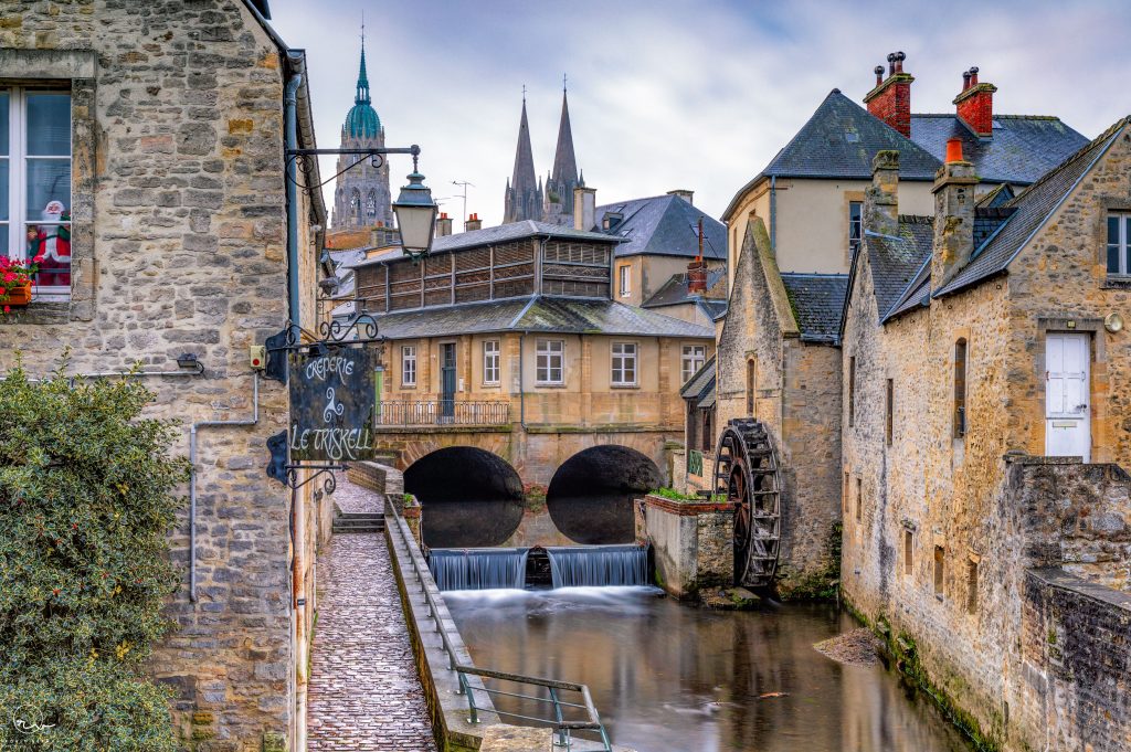 Historic watermill on a picturesque canal in Bayeux, France, showcasing Normandy's charm.
